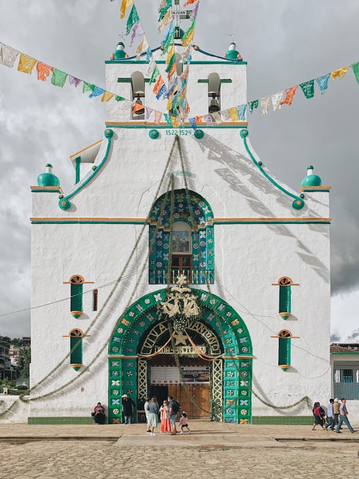 Vivid facade of a church in San Juan Chamula, Mexico, with traditional decorations and festive flags.