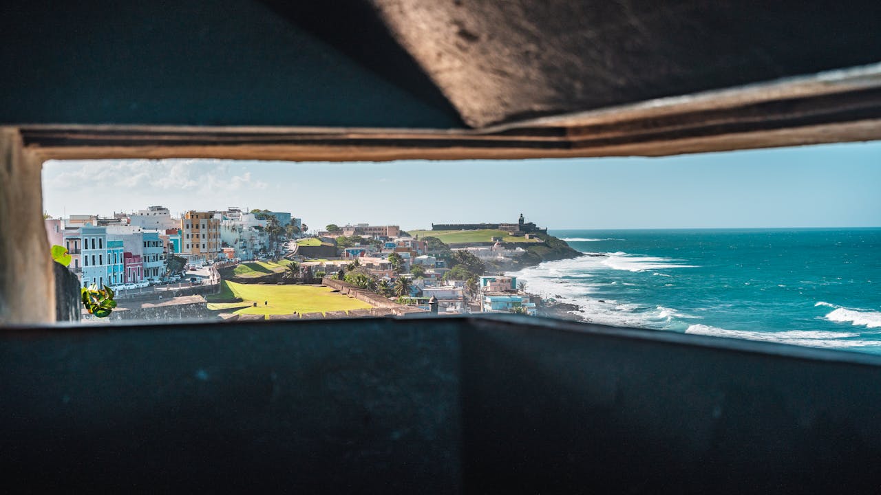 about-01 Scenic view of San Juan's coastal cityscape through fortifications.