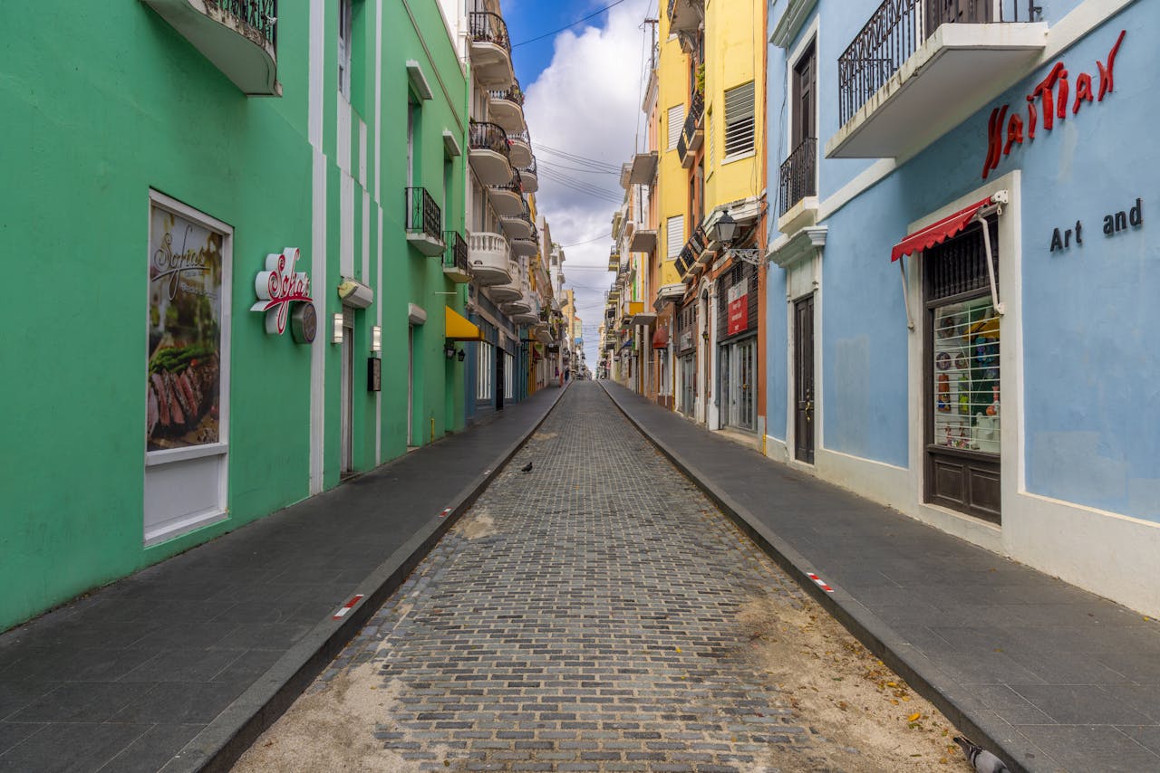 about-02 Vibrant and narrow cobblestone street in Old San Juan, showcasing colorful architecture and urban charm.